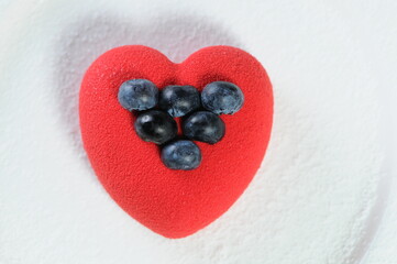 red dessert in the background of a heart decorated with berries
