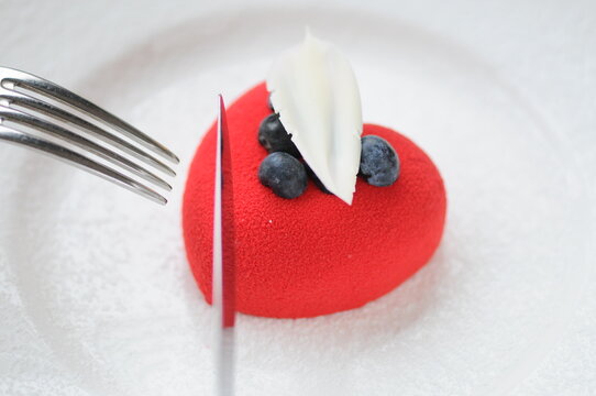 red dessert in the background of a heart decorated with berries in a white plate macro photo
