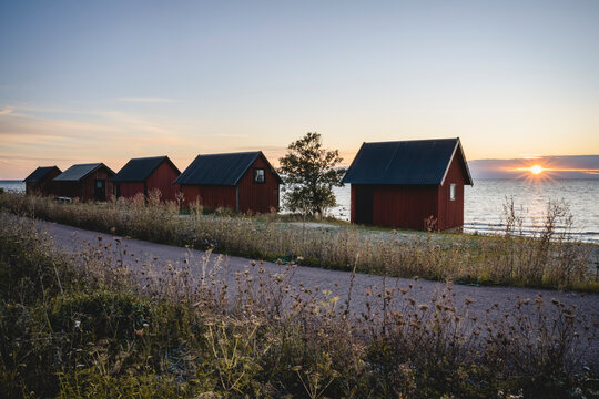 Sweden, Oland, Byxelkrok, Footpath stretching behind coastal fishing huts at sunset