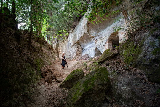 Senior woman standing in front of cave under tree