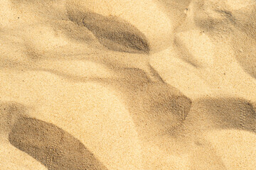 Fototapeta na wymiar Close-up of yellow sand on the beach. Small grains of sand on a clean beach. Toned photo with low depth of field.