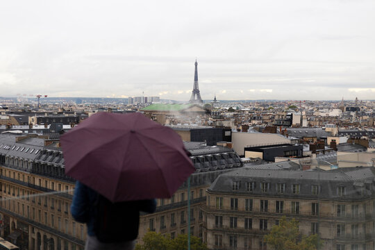 France, Ile-de-France, Paris, City skyline with man standing with umbrella in foreground