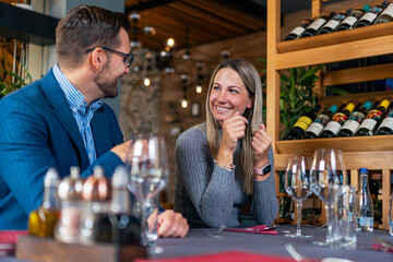 Beautiful happy smiling elegant couple sitting in restaurant, waiting for their dinner and talking.