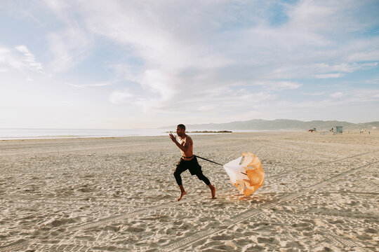 Man running with parachute on beach