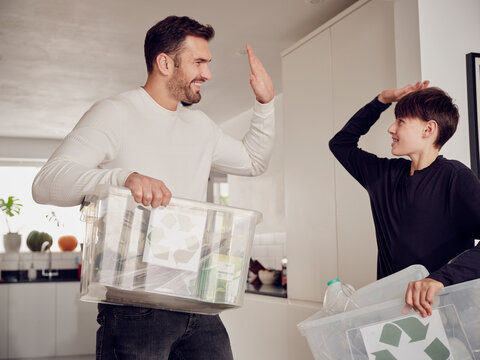 UK, London, Buckinghamshire, generations, sustainability, home, recycling, Dad and son having fun and high five after sorting the recycling.