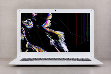 white laptop with a broken screen on a gray background close-up front view