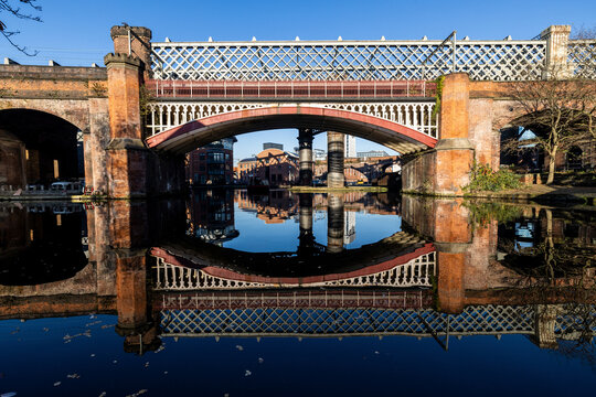 UK, England, Manchester, Arch bridge reflecting on surface of canal