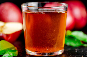 A full glass of apple juice with leaves.