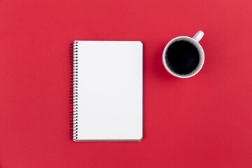 Blank notepad and coffee cup on red background, flat lay.