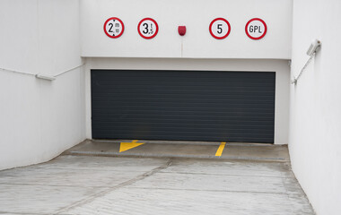 Underground parking garage door. A dark grey metallic automatic garage door is closed at the...