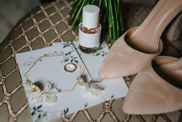 Stylish beige shoes, perfume, earrings, and ring on chair background. Bride accessories. Letters from the bride and groom. Side view.