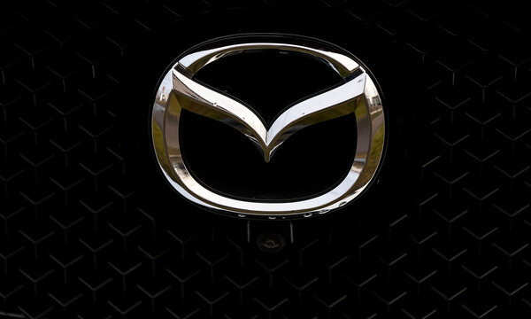 The logo sign of Mazda Japanese car company against dark background in the front part of an SUV. Romania, 2023.