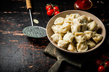 Dumplings on a cutting board with cherry tomatoes. 