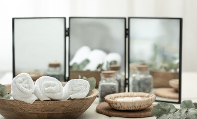 Spa composition with towels in a wooden plate on a blurred background.