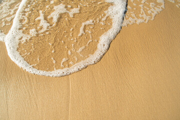 Close-up of a beach with a calm transparent wave. Romantic sea coast with golden sand.