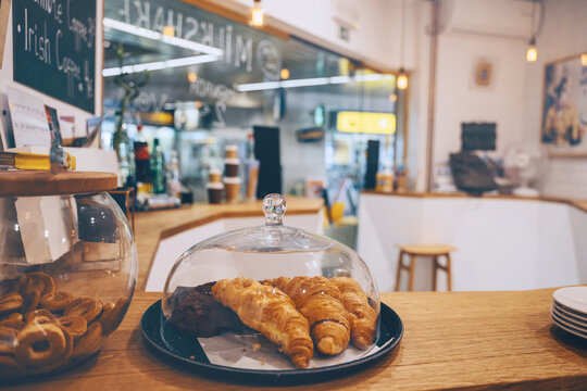 Interior details at the bakery and coffee shop. Bistro showcase with shelves of freshly croissants. Local small businesses at food service.