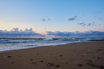 Sea coastline with waves. Baltic sea beach against dramatic cloudy sky at sunset. Panoramic nature landscape