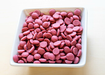 Ruby chocolate flakes in a white ceramic bowl