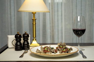 tartar in chips in a plate on the table with a glass of red wine
