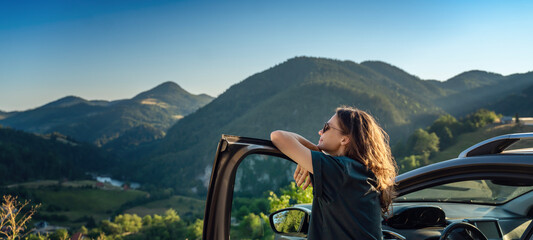 Young beautiful woman traveling by car in the mountains, summer vacation