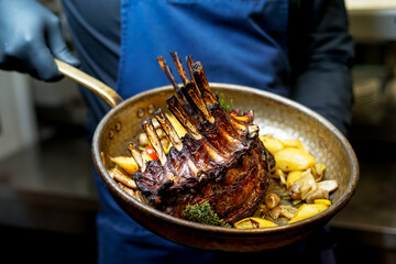 fried rack of lamb in a pan in the hands of the chef
