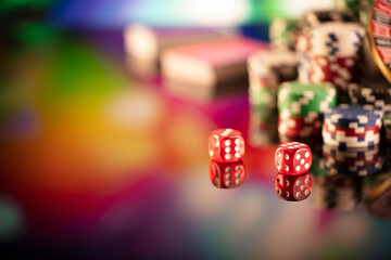 Casino theme.  Gambling games. Dices and poker chips on a colorful bokeh background.