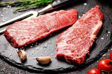 Raw steak on a stone board. On a black background.