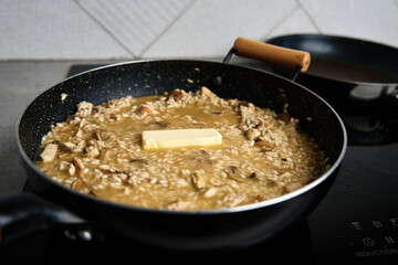 Process of cooking risotto. Arborio rice and piece of butter in frying pan in home kitchen. Italian cuisine dish