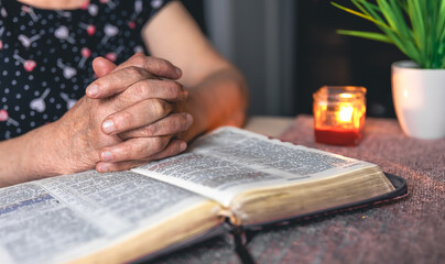 Naklejka premium An old woman reads the Bible, hands close up.