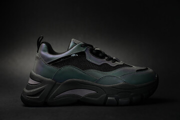 Stylish sneaker with neon gradient on black background. Glowing creative fashion shoe