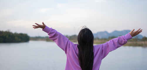 Asian girl standing with her arms outstretched, giving a feeling of freedom. Emotional release, relaxation and inspiration.