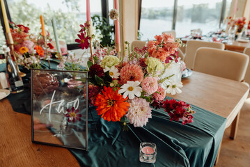 Decoration and table setting in the restaurant for the holiday. Professional floristry with fresh flowers. Decoration with candles and green glass and fabric details