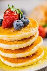 Pancakes with honey and berries on a plate.