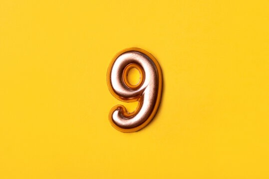 Metal number nine on a yellow background. Top view.