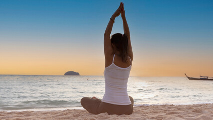 Happy lifestyle woman practices yoga on the beach with sunset sky scene background