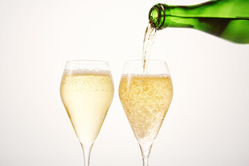 Sparkling wine pours from green bottleneck, creates bubbles.