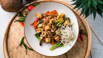 Udon noodles stir fry with chicken, carrots, onions, broccoli, sweet peppers and green sprouts.