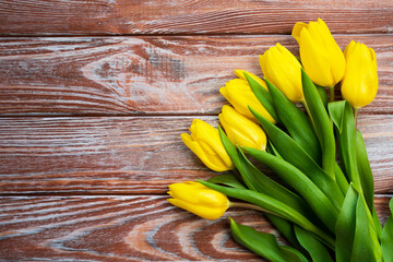 Flatlay composition with bouquet of yellow tulips on a wooden background. Top view. Place for text. Selective focus.