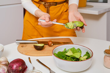 Unrecognizable woman removing avocado out of the shell with spoon