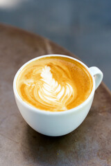 A cup of cappuccino coffee on a table in a cafe. Coffee hot drink in a ceramic cup for breakfast in the morning.