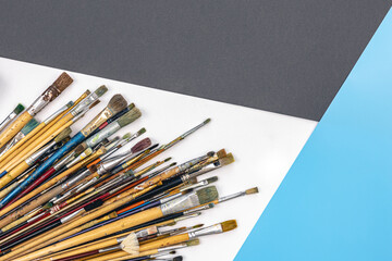 Many brushes for painting on a colored background, top view.
