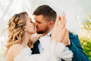 the bride and groom hold hands with wedding rings and kiss. Selective focus.