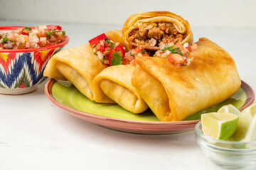 Delicious chimichanga or burrito, classic Mexican cuisine on a wooden board with salsa sauce, one...