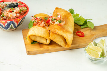 Traditional chimichanga with salsa sauce, Mexican traditional cuisine. Light background.
