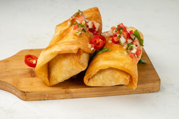 Chimichanga is a Mexican traditional tortilla snack stuffed with minced meat, beans and various spices, close-up.