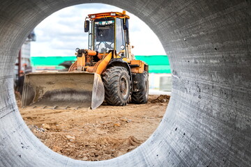 Bulldozer or loader moves the earth at the construction site against the blue sky. An earthmoving...