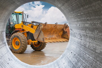 Fototapeta na wymiar A large front loader transports crushed stone or gravel in a bucket at a construction site or concrete plant. Transportation of bulk materials. Construction equipment. Bulk cargo transportation.
