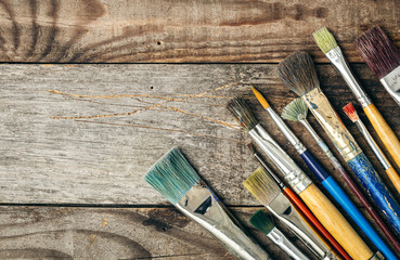 Paint brushes of different sizes on a wooden background, flat lay.