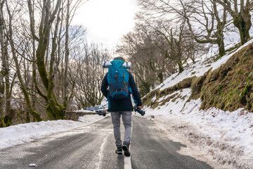 Obraz premium Photographer man walking on a snowy road, enjoying winter photography