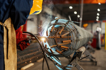 Close up of a metallurgy worker welding metal parts in factory.